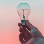 hand holding lightbulb at sunset