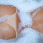 nude woman in bubble bath with summer tan lines
