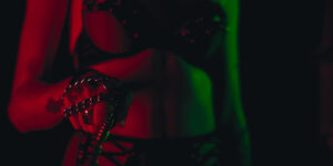 kinky woman in dim lighting preparing to use a strap-on