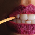 woman with lipstick with lit match in mouth
