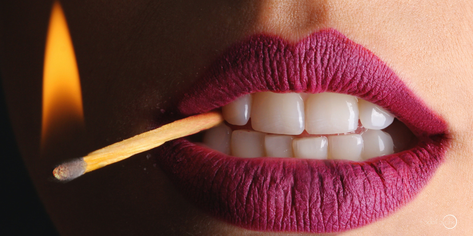 woman with lipstick with lit match in mouth