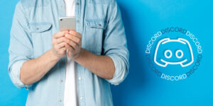 man holding smart phone next to discord logo