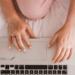 Woman wearing pink pijamas sitting in bed with her laptop