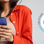 Woman wearing an orange shirt holding a blue phone