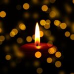 Red candle burning with christmas light in the background