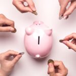 piggy pang with hands holding coins around it